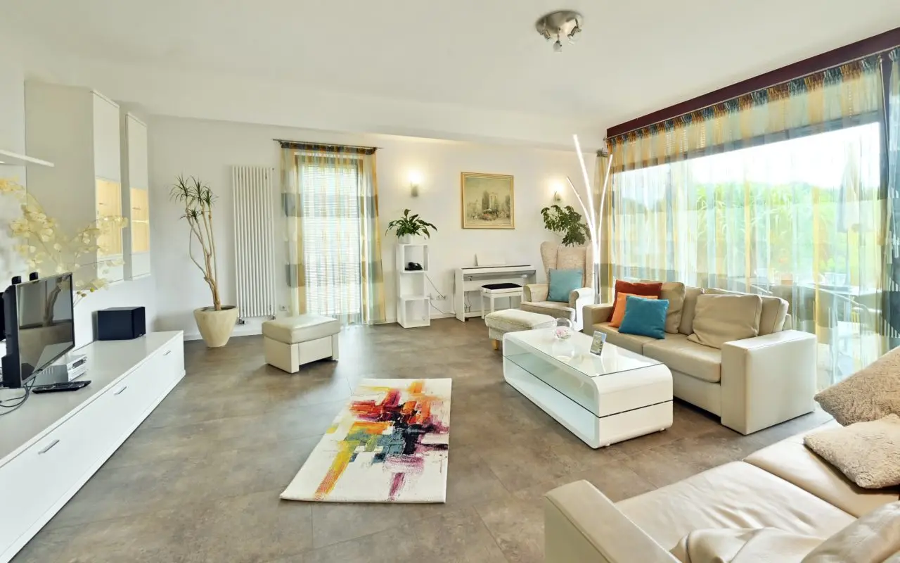 Heller, geräumiger Wohnbereich einer Suite im Landhaushotel Hof Wasserkuppe mit Sofa, TV und Zugang zur Terrasse.