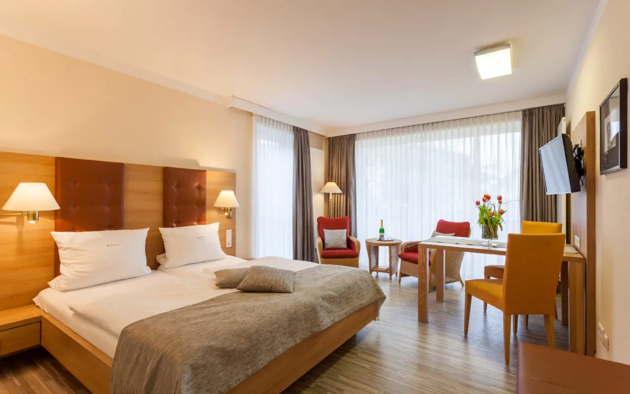 Gemütliches Doppelzimmer mit Sitzbereich und Esstisch im Landhaushotel Hof Wasserkuppe.