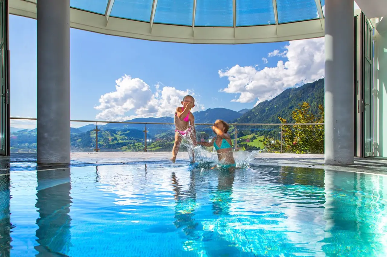 Beheizter Panoramapool mit Bergblick im Wellness Hotel Zinnkrügl, Kinder spielen im Wasser.