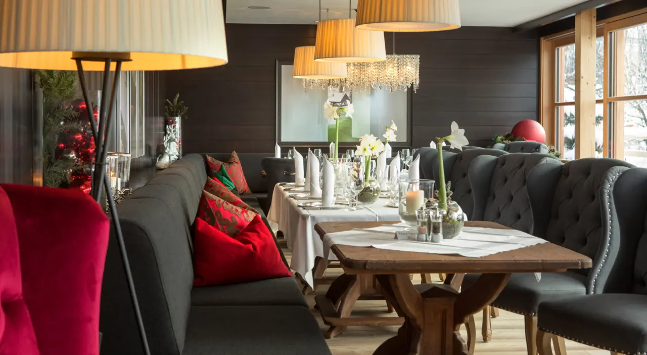 Festlich gedeckter Restaurantbereich im Wellness Hotel Zinnkrügl mit gemütlichen Sitzgelegenheiten und Winterblick.