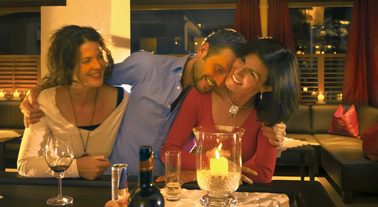 Fröhliche Gäste genießen einen Abend in der Hotelbar des Wellness Hotel Zinnkrügl mit Kerzenschein und Getränken.