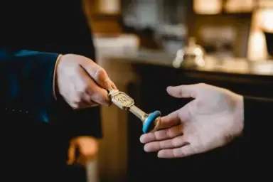 Hotel Schlüsselübergabe an der Rezeption des Hotel Stadt Hamburg. Gast erhält traditionellen Zimmerschlüssel.