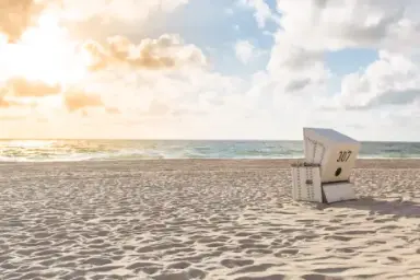 Strandkorb am Sandstrand mit Meerblick und Sonnenlicht, ideal für Entspannung im Hotel Stadt Hamburg.