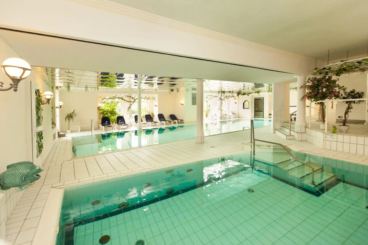 Grosszügiger Innenpool im Ferienhotel Haus Becker mit Liegebereich, Tageslicht und Pflanzen-Dekoration.