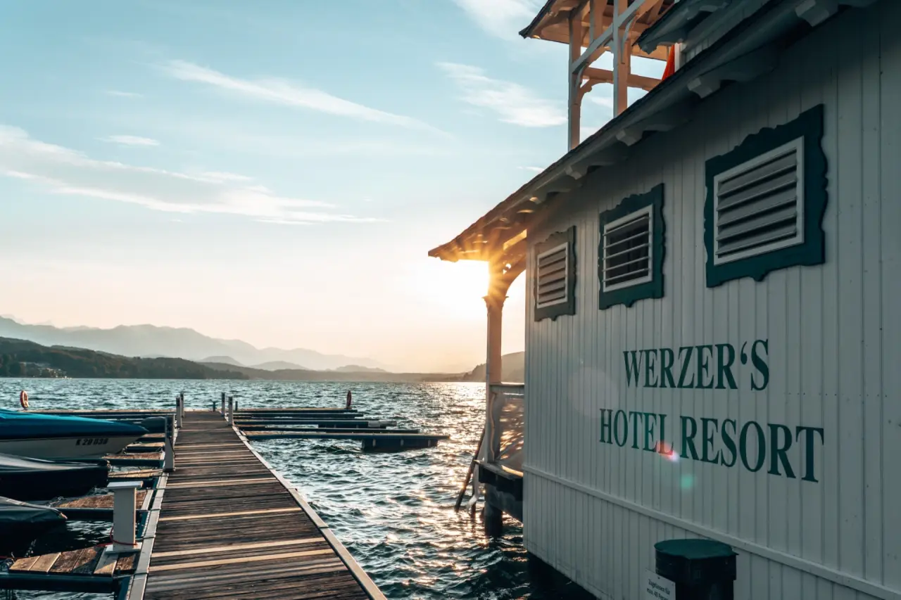 Abendstimmung am Wörthersee mit Steg und dem Werzers Hotel Resort Pörtschach bei Sonnenuntergang und Bergpanorama.