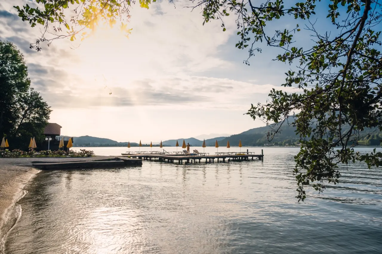Sonnenuntergang am privaten Badesteg mit Liegestühlen und Sonnenschirmen am Wörthersee im Werzers Hotel Resort Pörtschach.