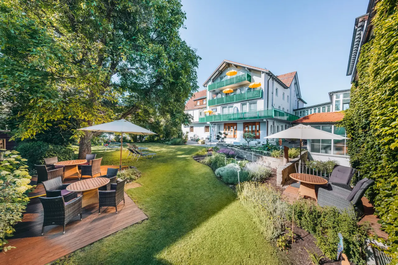 Aussenansicht des Kneipp- & Wellvitalhotel Edelweiss mit gepflegtem Garten, Terrassen und Liegewiesen unter blauem Himmel.