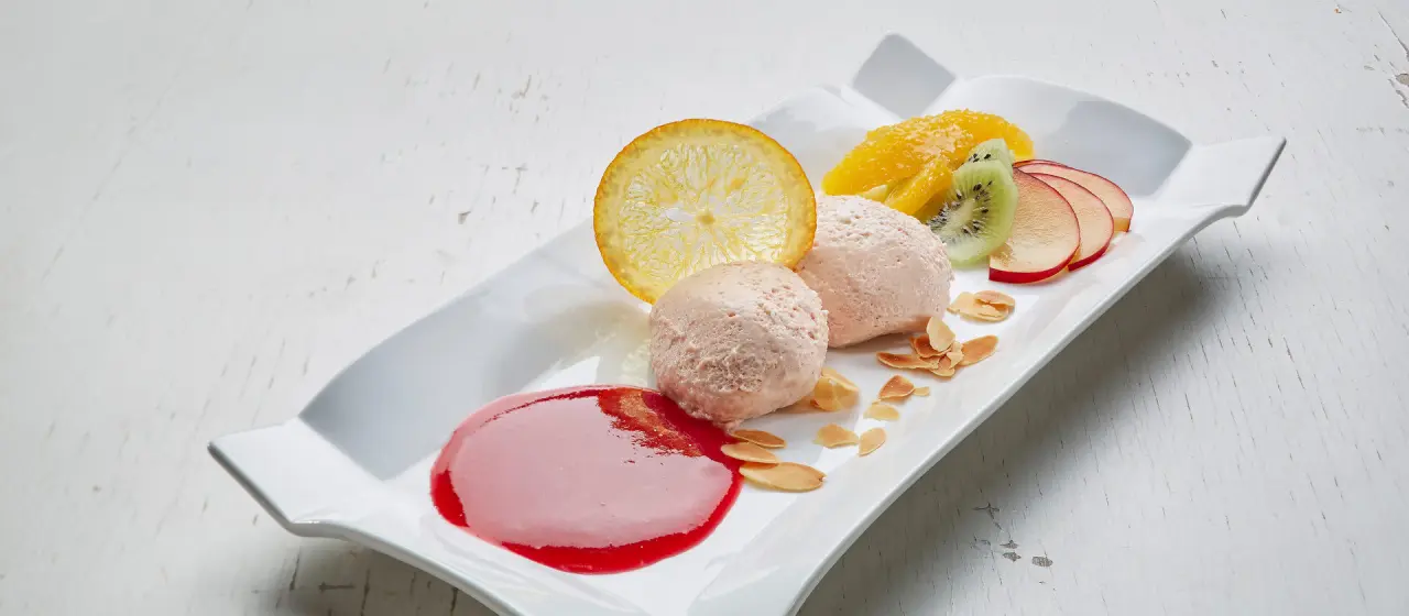 Ansprechend angerichtetes Dessert mit Fruchteis, frischen Früchten und Mandelsplittern im Kneipp- & Wellvitalhotel Edelweiss.