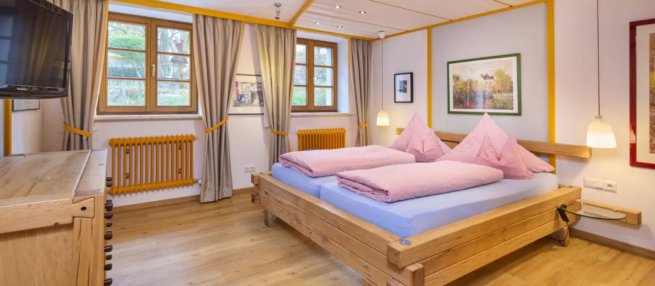 Gemütliches Doppelzimmer mit Holzbett und Blick ins Grüne im Kneipp- & Wellvitalhotel Edelweiss.