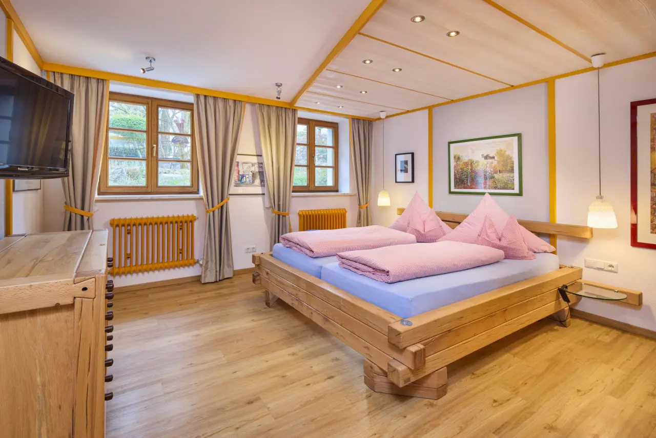 Gemütliches Doppelzimmer mit Holzbett und Blick ins Grüne im Kneipp- & Wellvitalhotel Edelweiss.