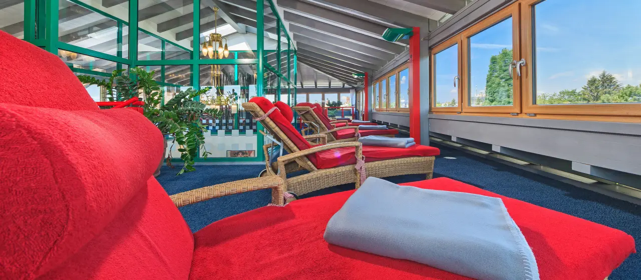 Entspannungsbereich mit roten Liegen und Panoramablick im Kneipp- & Wellvitalhotel Edelweiss