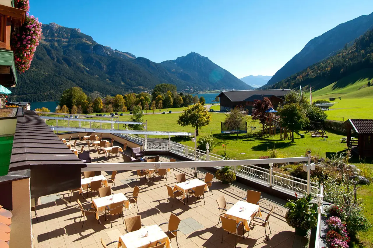 Sonnige Restaurantterrasse des Hotel Das Pfandler mit Blick auf den Achensee und die umliegende Bergwelt.