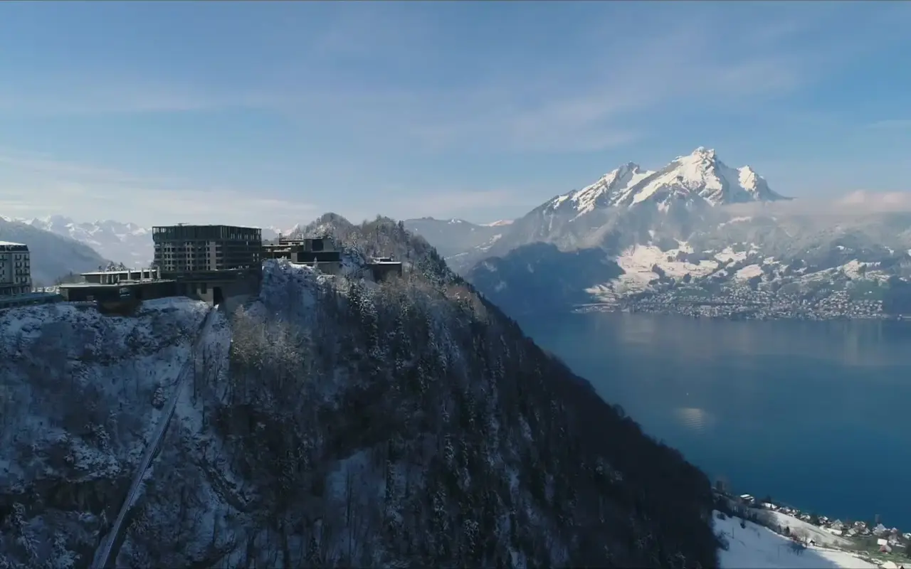 Winterpanorama des Bürgenstock Resort Lake Lucerne mit schneebedeckten Bergen, Vierwaldstättersee und Hotelanlage.