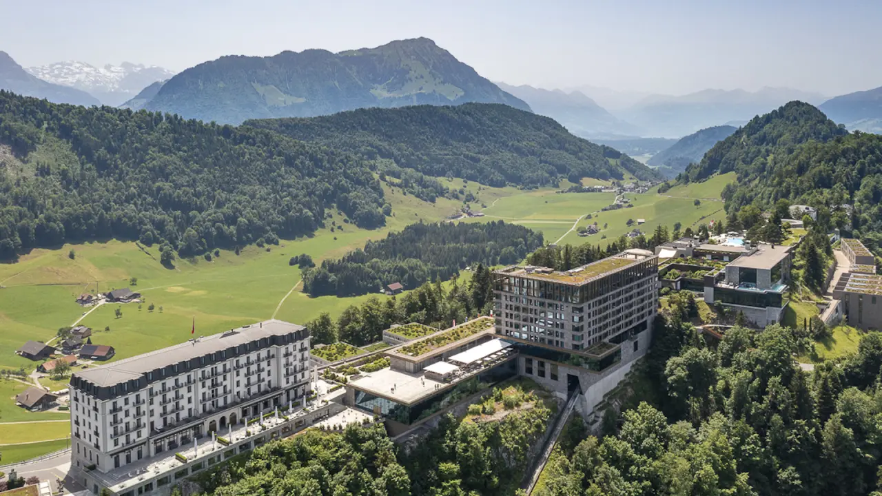 Luftaufnahme des Bürgenstock Resort Lake Lucerne mit luxuriösen Hotelgebäuden und Infinity Pool in alpiner Landschaft.
