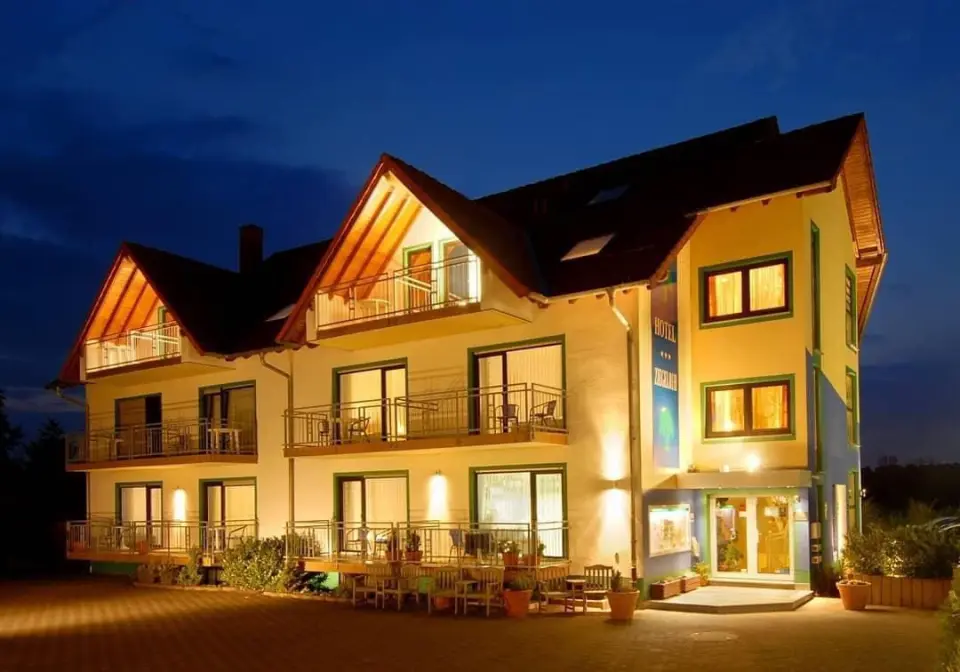 Beleuchtete Aussenansicht des Wellnesshotel Ziegelruh bei Nacht. Das einladende Hotelgebäude mit Balkonen strahlt Wärme aus.