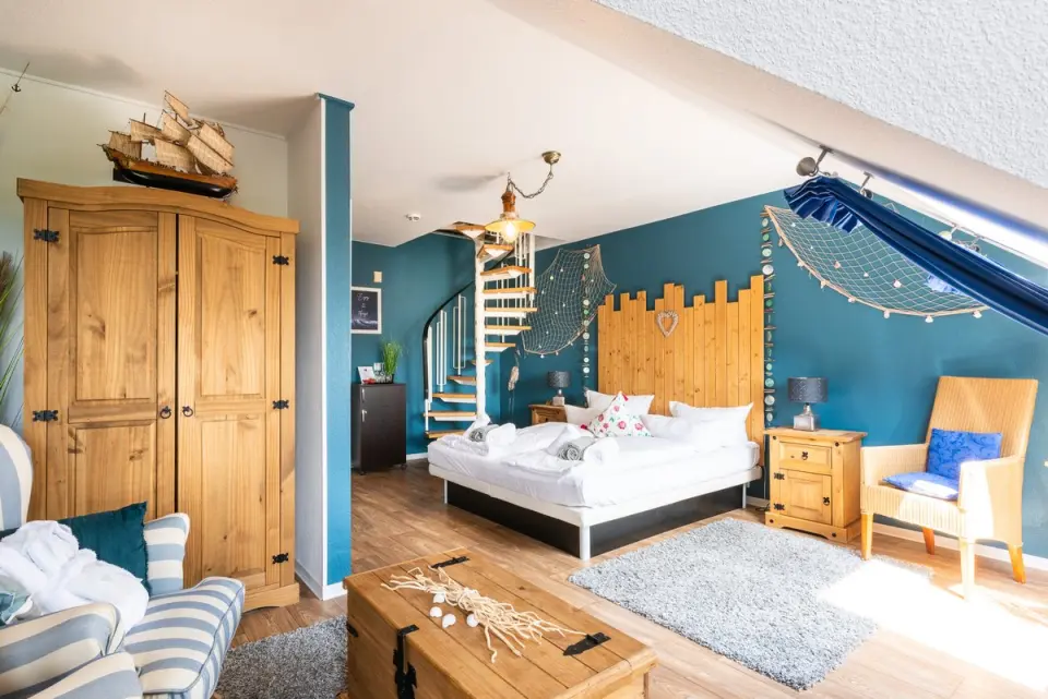 Maritim eingerichtetes Hotelzimmer mit Doppelbett, Wendeltreppe und Holzelementen im Wellnesshotel Ziegelruh.
