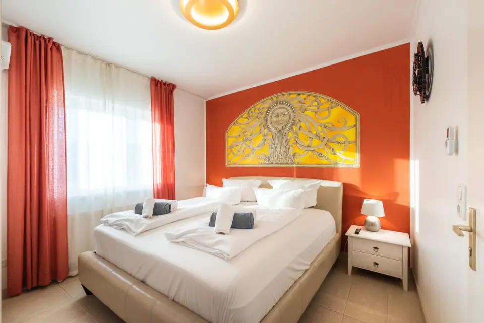 Helles Doppelzimmer mit orangefarbener Wand und Sonnen-Wandbild im Wellnesshotel Ziegelruh.