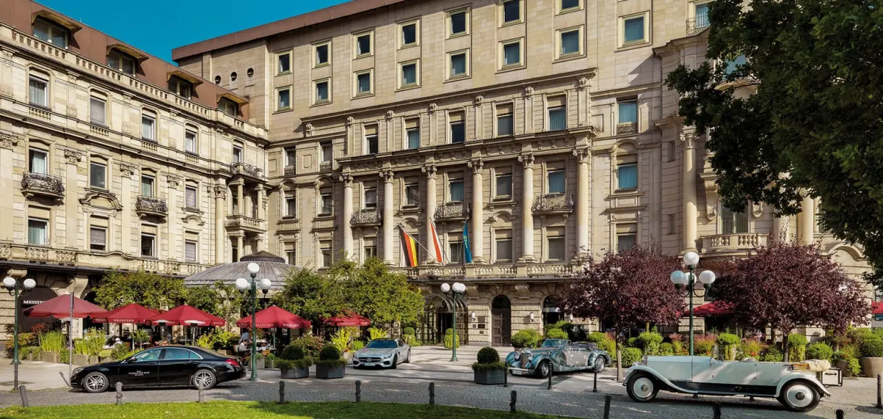Historische Fassade des Hotel Nassauer Hof in Wiesbaden mit elegantem Eingangsbereich, Oldtimern und Außenterrasse.