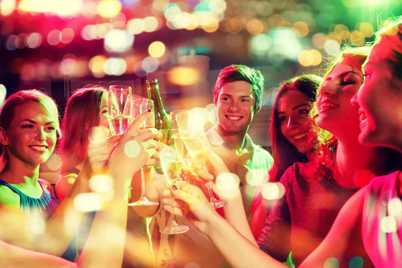 Fröhliche Gäste stoßen mit Sektgläsern an bei einem geselligen Abend im AVIVA****s make friends Hotel.