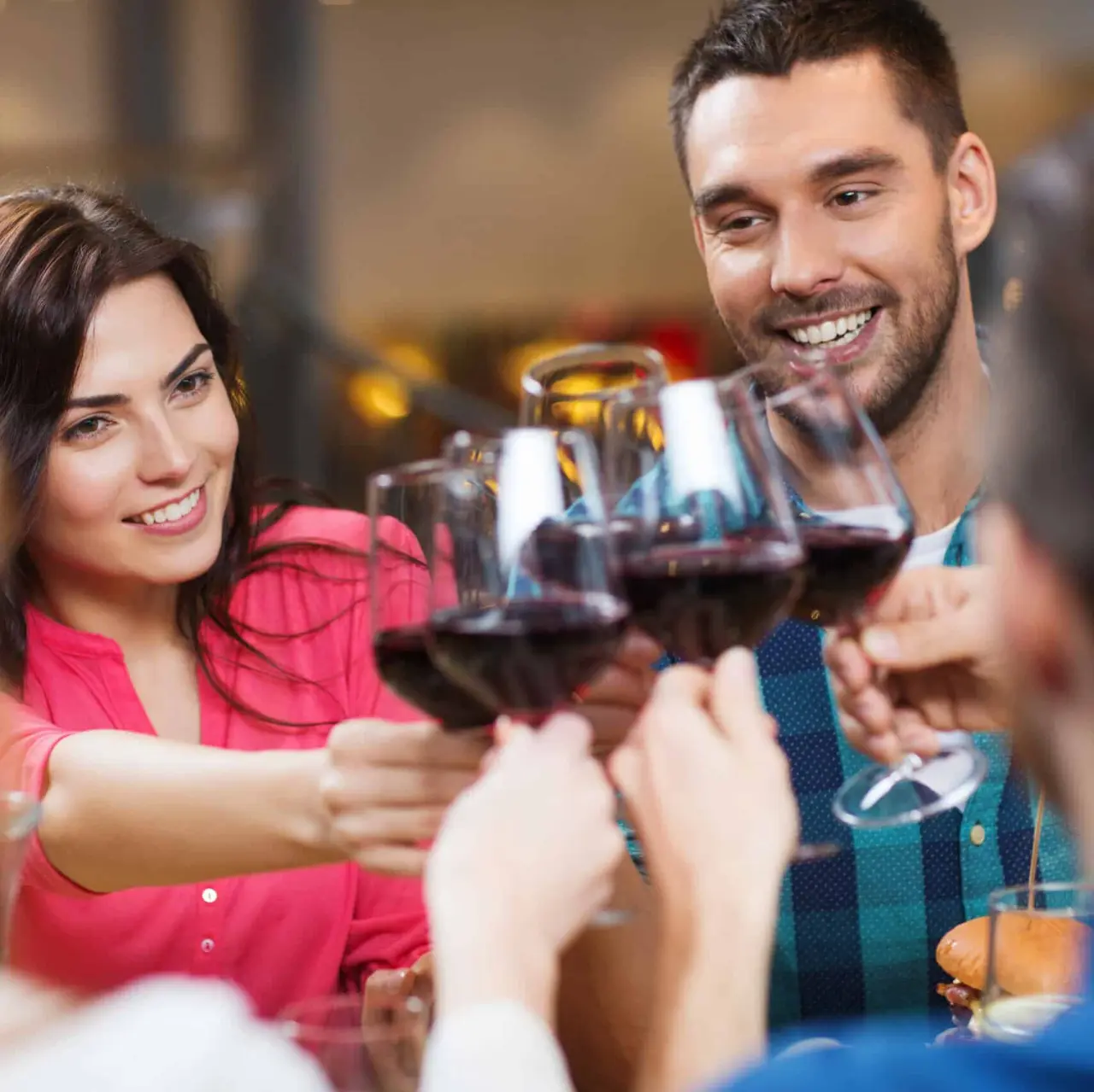 Freunde stoßen mit Rotwein an in der geselligen Atmosphäre des AVIVA****s make friends Hotels.