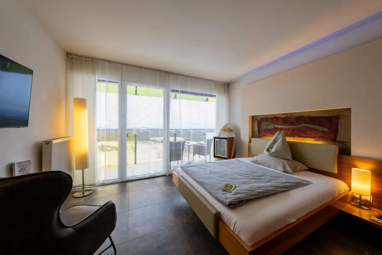 Modernes Doppelzimmer mit Balkon und Blick ins Grüne im AVIVA****s make friends Hotel.