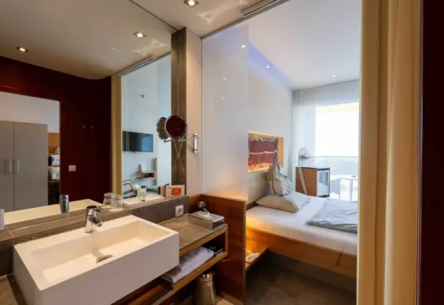 Modernes Hotelzimmer mit offenem Badbereich und Balkon im AVIVA****s make friends.
