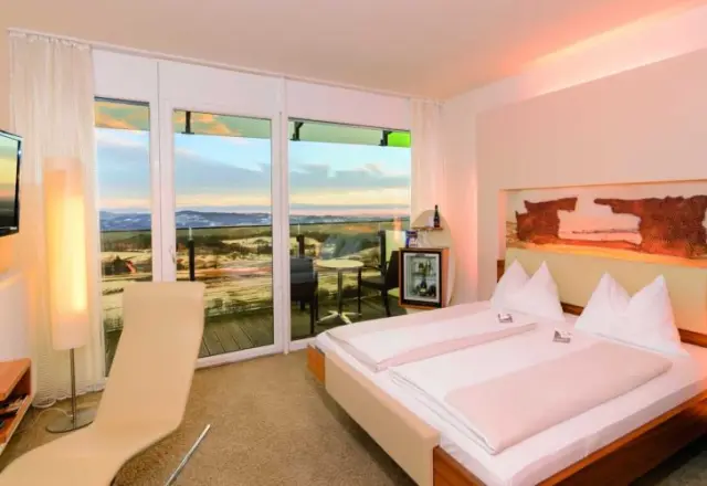Komfortables Doppelzimmer im Hotel AVIVA****s mit Balkon und weitem Blick über die winterliche Landschaft.