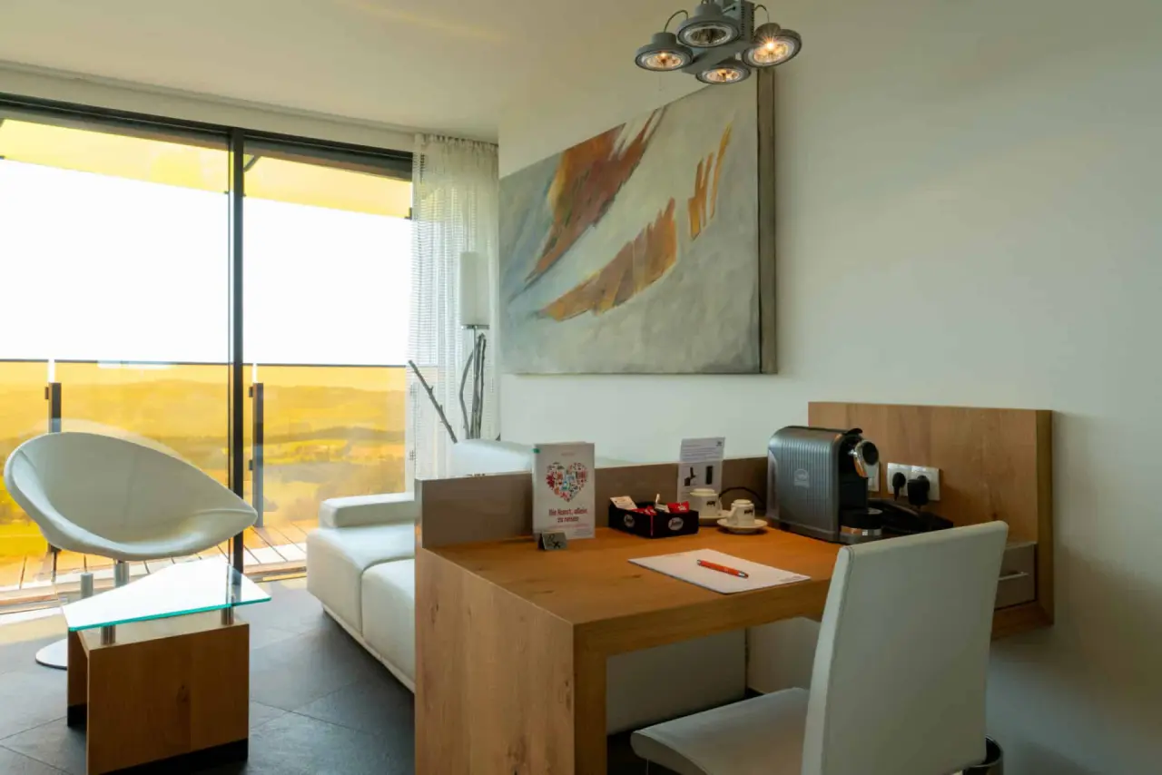 Modernes Hotelzimmer im AVIVA****s make friends mit Schreibtisch, Kaffeemaschine und Sitzgelegenheit. Panoramablick.