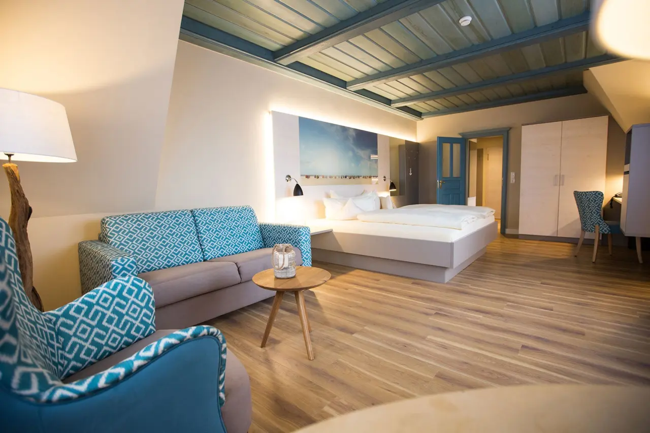 Modernes Hotelzimmer im Hotel Seeblick mit Doppelbett, Sofa in Türkis und Holzboden. Gemütliche Einrichtung für Ihren Aufenthalt.