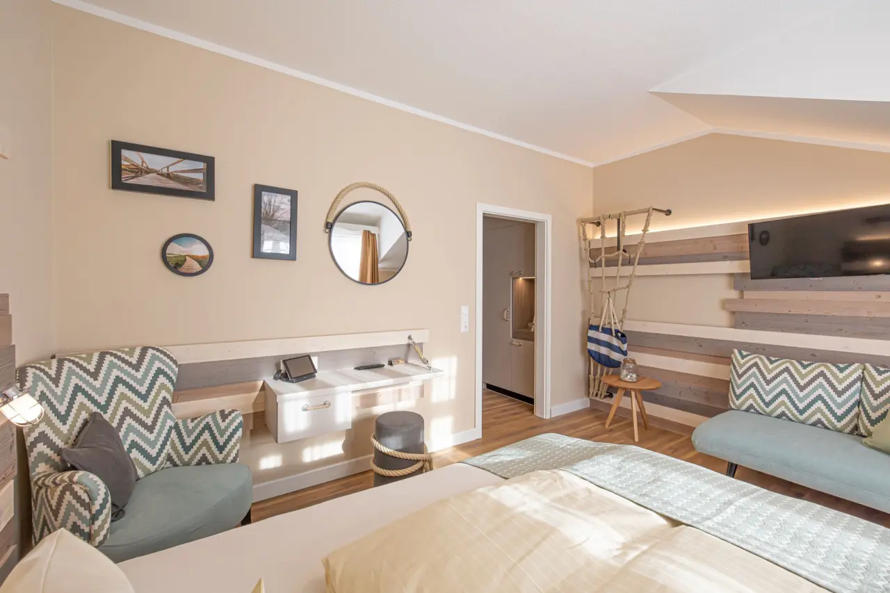 Gemütliches Hotelzimmer im maritimen Stil mit Doppelbett, Sessel und Schreibtisch im Hotel Seeblick.