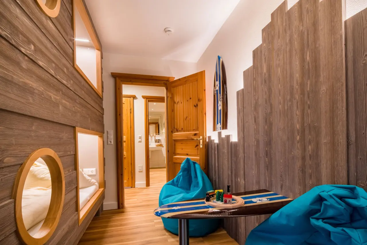 Einzigartiges Familienzimmer im Hotel Seeblick mit Holzbettnischen, Surfbrett-Deko und Spielbereich.