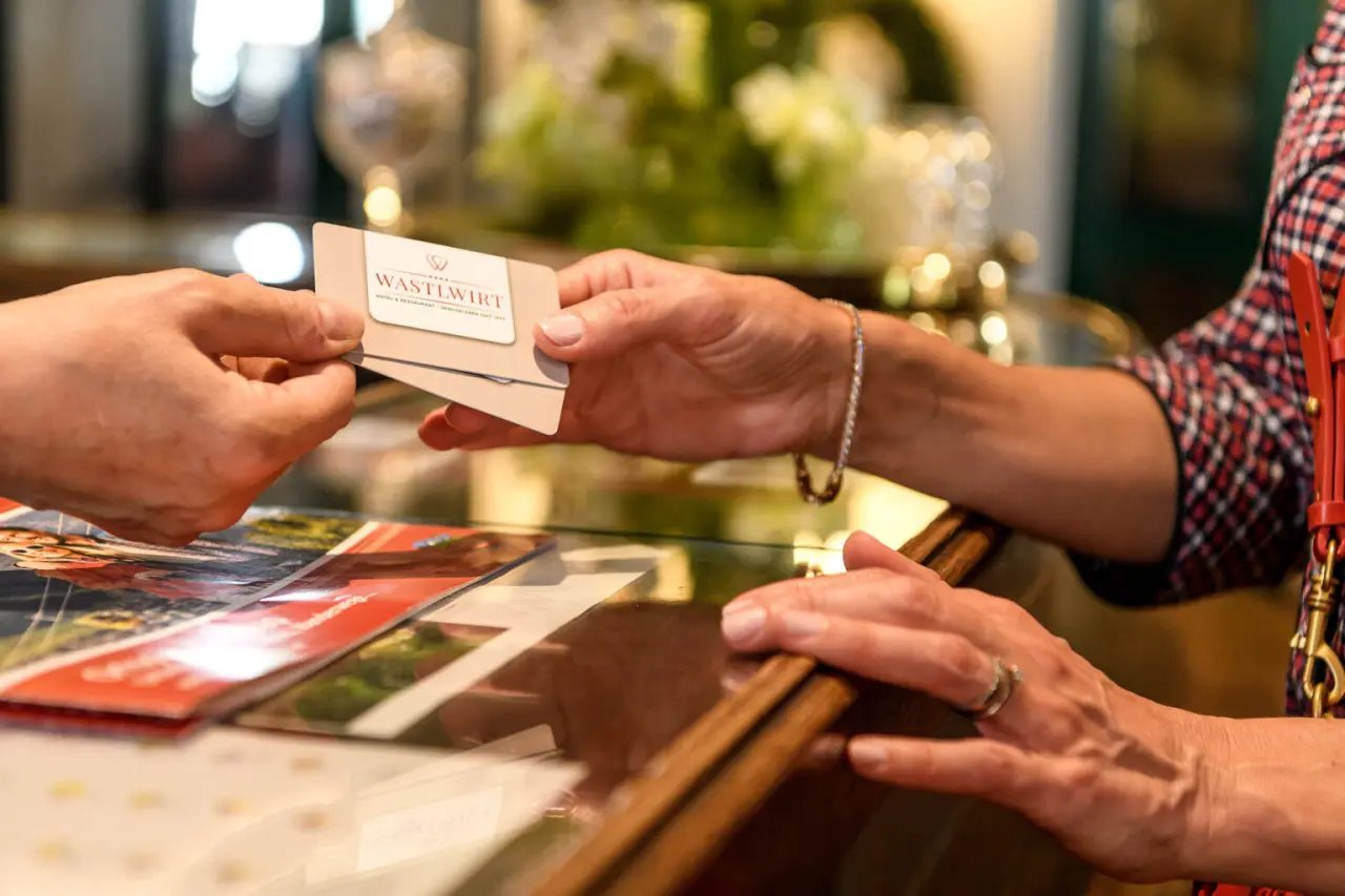 Gast erhält Schlüsselkarte oder Kundenkarte des Romantik Hotel Wastlwirt an der Rezeption.