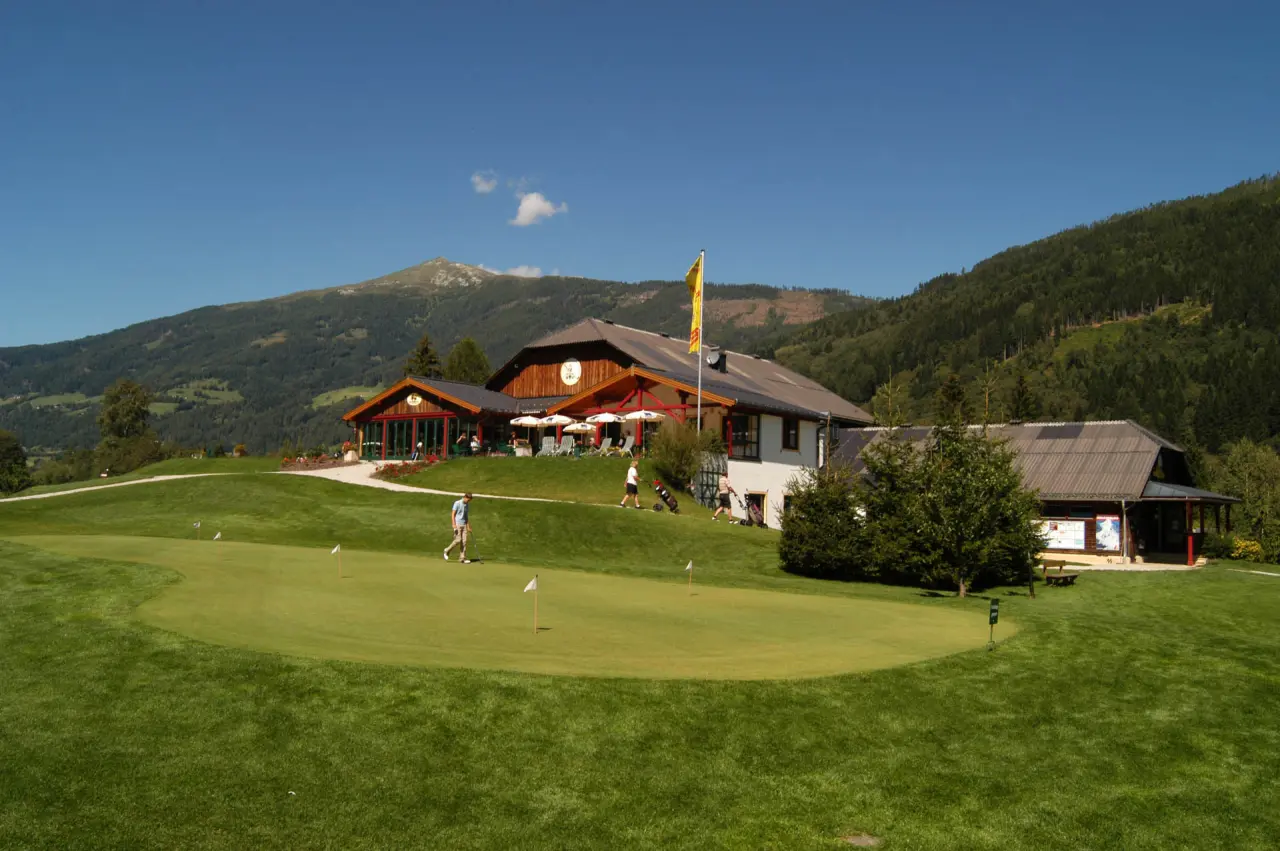 Golfplatz mit Hotelgebäude und Alpenpanorama am Romantik Hotel Wastlwirt.
