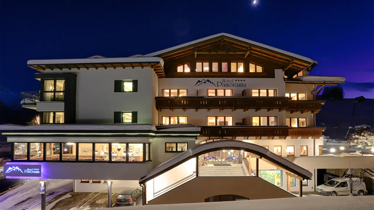 Winterliche Aussenansicht des Wellness- & Familienhotel Panorama bei Nacht, mit warm beleuchteten Fenstern und Schnee.