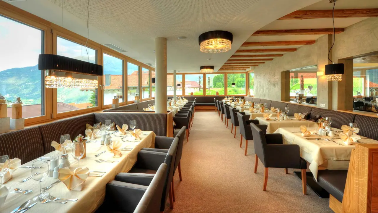 Heller Restaurantbereich mit elegant gedeckten Tischen und Bergblick im Wellness- & Familienhotel Panorama.