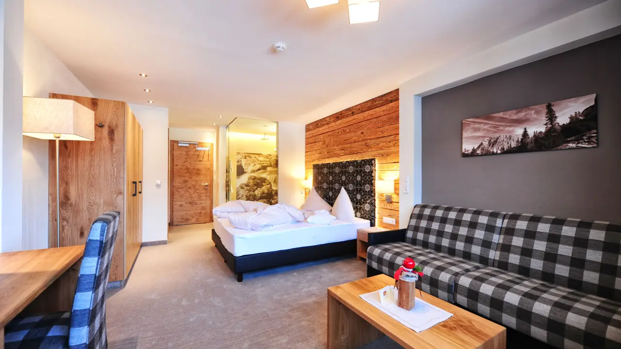 Gemütliches Doppelzimmer mit Holzelementen und Sofa im Wellness- & Familienhotel Panorama.