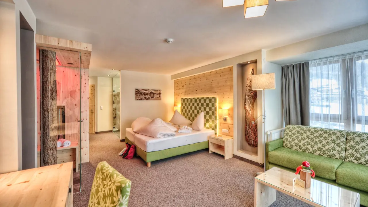 Geräumiges Hotelzimmer mit privater Sauna und gemütlicher Sitzecke im Wellness- & Familienhotel Panorama.