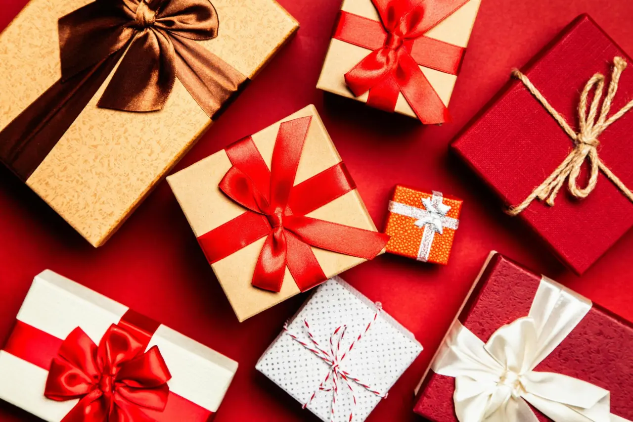 Bunte Geschenkboxen mit Schleifen auf rotem Hintergrund, ideal für Gutscheine im Castanea Resort Hotel.