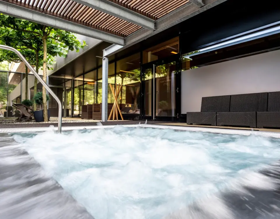 Sprudelnder Outdoor-Whirlpool mit moderner Architektur und Grünanlage im Sonne Mellau - Feel good Hotel.