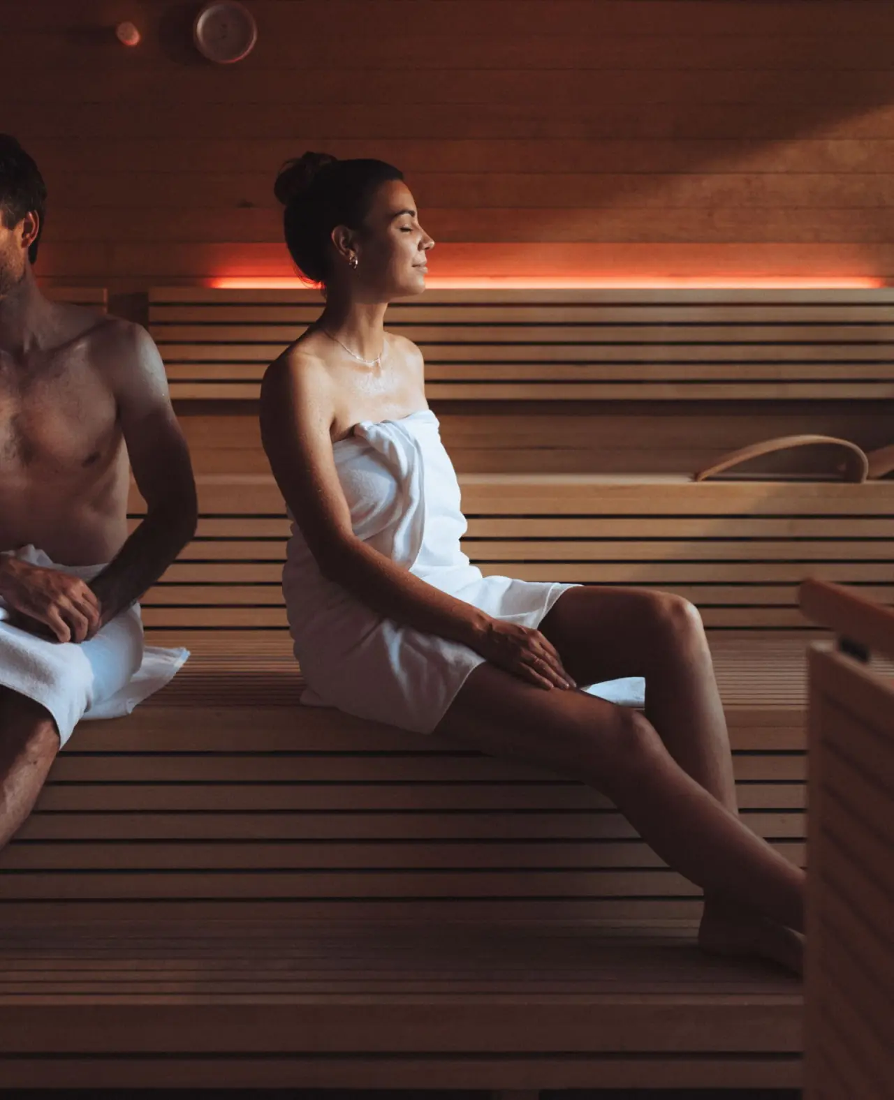 Paar entspannt in der modernen Sauna mit warmem Licht im Sonne Mellau - Feel good Hotel.