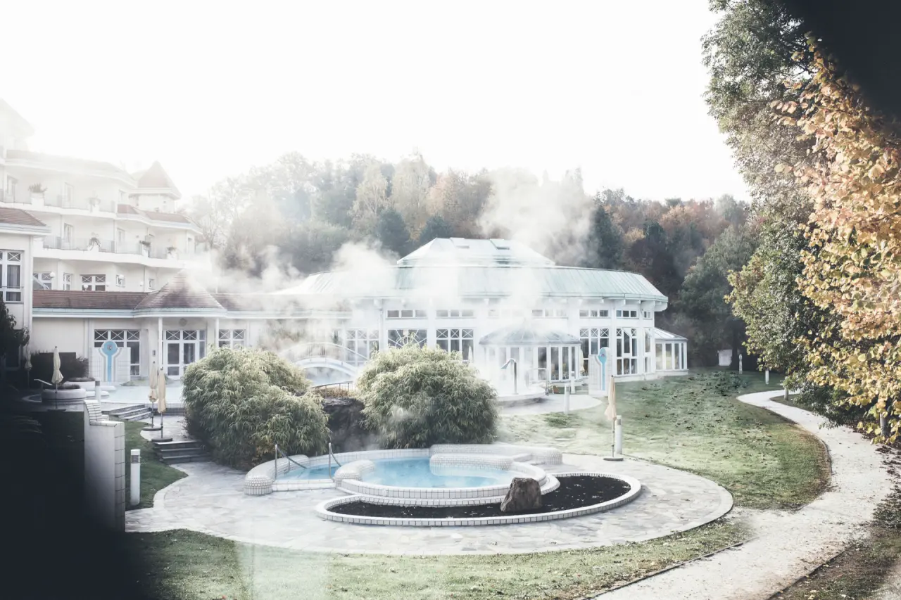 Dampfende Thermalbecken im Aussenbereich des REDUCE Hotel Thermal ****S umgeben von herbstlicher Natur.