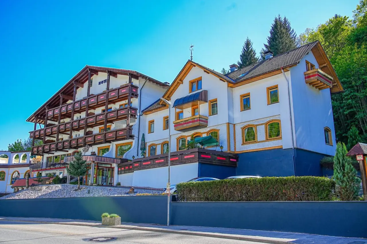Aussenansicht von Holzschuh’s Schwarzwaldhotel mit traditioneller Architektur, Balkonen und umgeben von grünen Bäumen unter blauem Himmel.