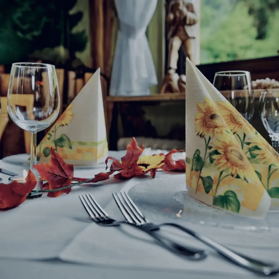 Festlich gedeckter Tisch mit herbstlicher Dekoration und Sonnenblumen-Servietten im Restaurant von Holzschuh’s Schwarzwaldhotel.