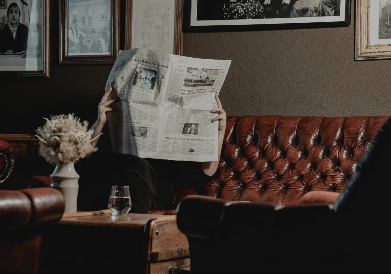 Gast liest Zeitung auf bequemer Leder-Couch im gemütlichen Loungebereich des Relaxhotel Sachsenbaude.
