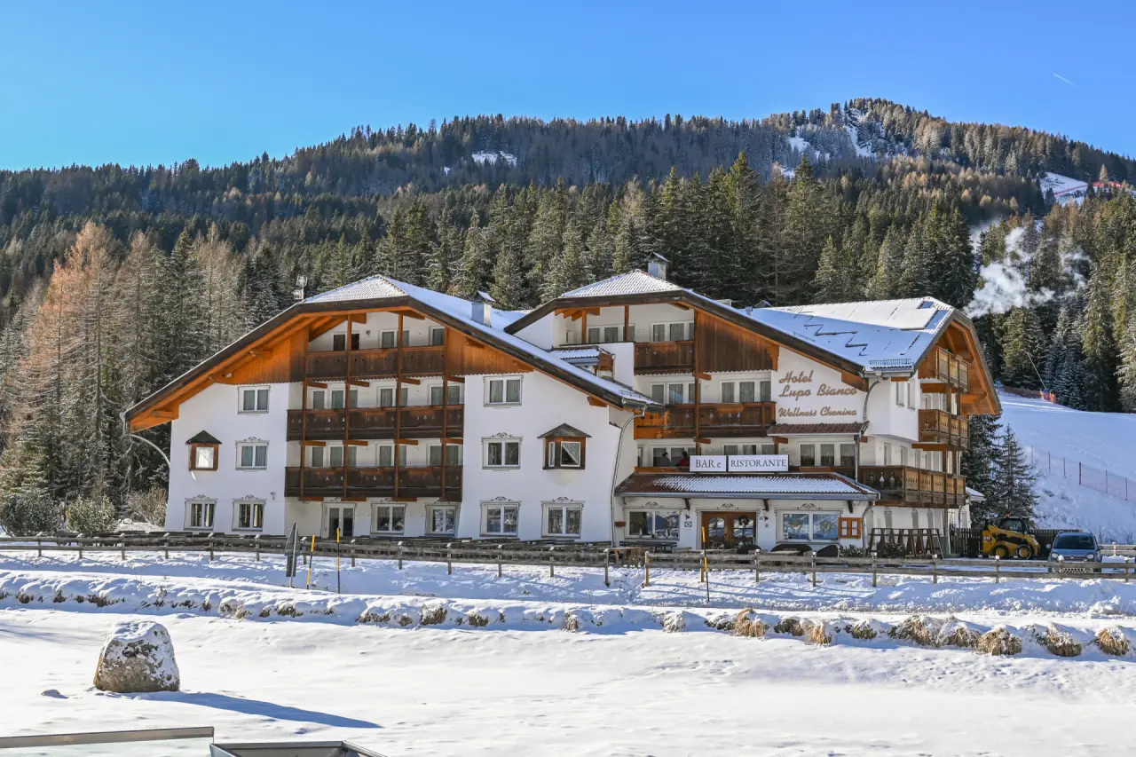 Hotel Lupo Bianco Wellness & Walking in Canazei – Außenansicht im Winter mit verschneiter Landschaft | Wellnesshotel Dolomiten