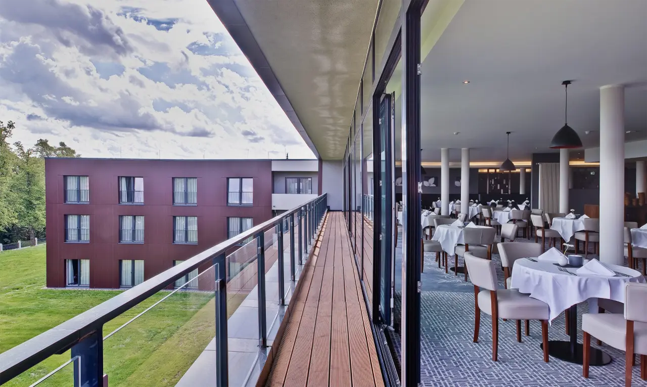 Blick vom Balkon auf die moderne Hotelfassade und den eleganten Restaurantbereich im Hotel Sante Royale Bad Brambach.