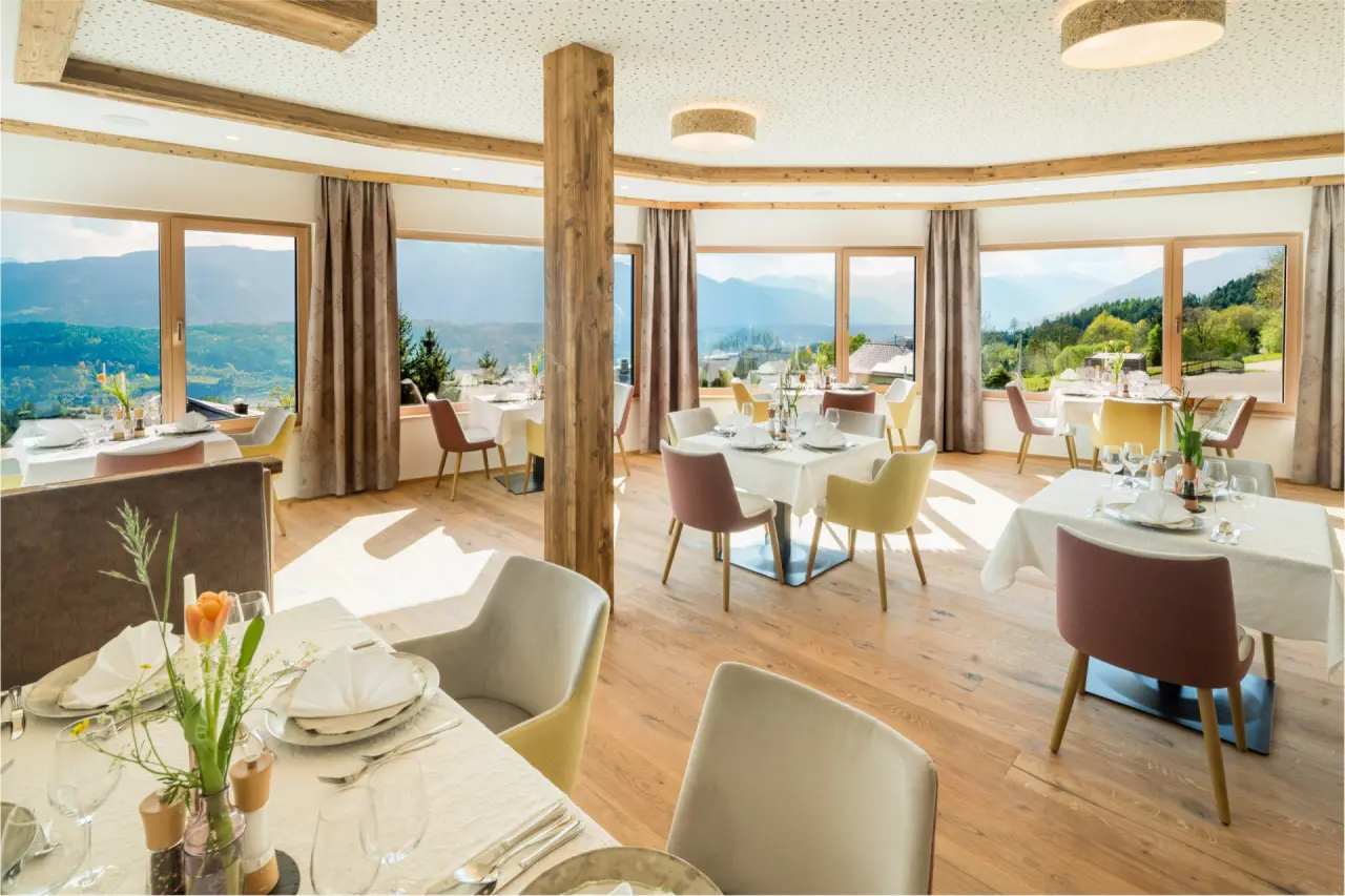Helles Restaurant im Naturhotel Alpenrose mit Panoramablick auf die umliegende Berglandschaft und stilvoll gedeckten Tischen.