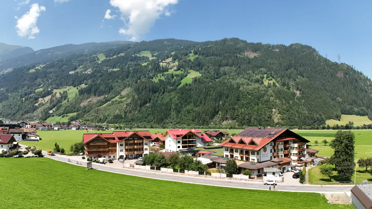 Aussenansicht des Ferienhotel Sonnenhof in den Bergen, umgeben von grünen Wiesen und Wäldern.