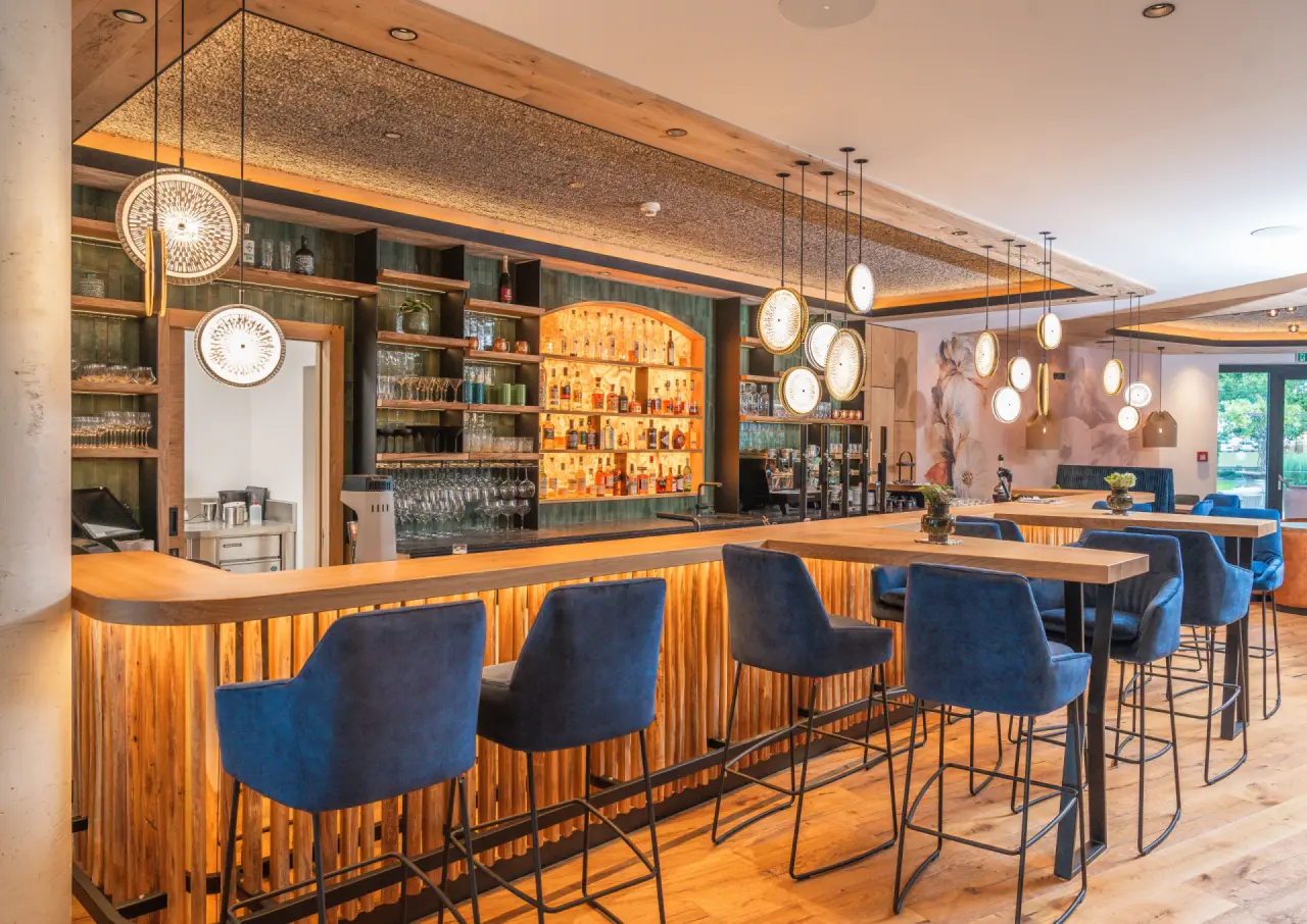 Modern eingerichtete Hotelbar mit blauen Barhockern und Holzdetails im Ferienhotel Sonnenhof.