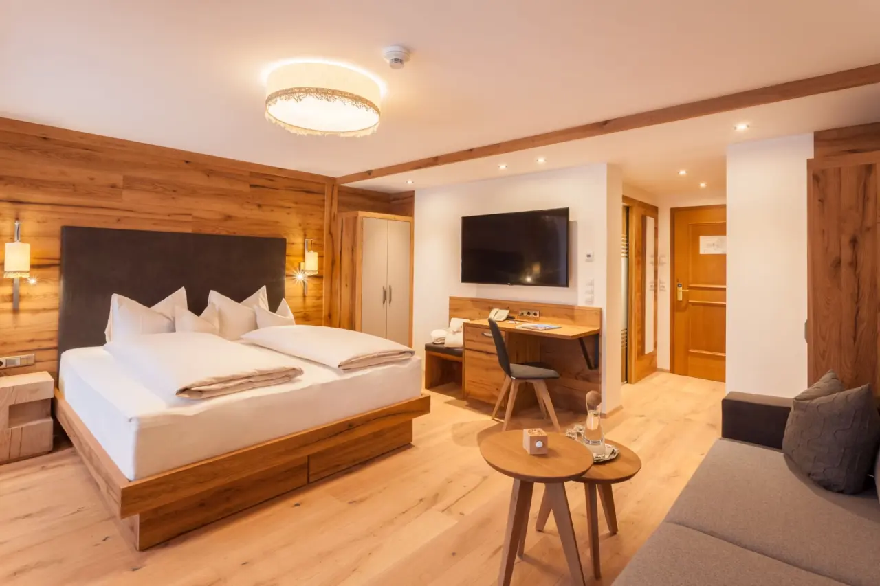 Komfortables Doppelzimmer im alpinen Stil mit Holzelementen, großem Bett und Schreibtisch im Ferienhotel Sonnenhof.